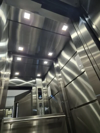 Interior de cabine modernizada em inox, com teto de iluminação LED e corrimão