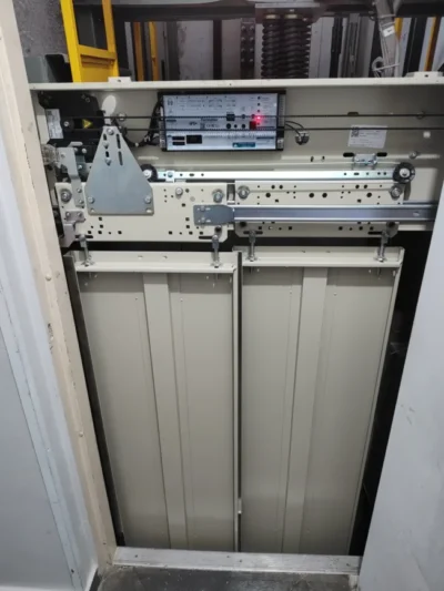 Operador de porta automática instalado no topo das portas de cabine de um elevador