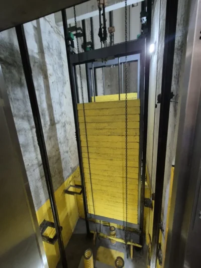 Poço do elevador com contrapeso pintado de amarelo e para-choques