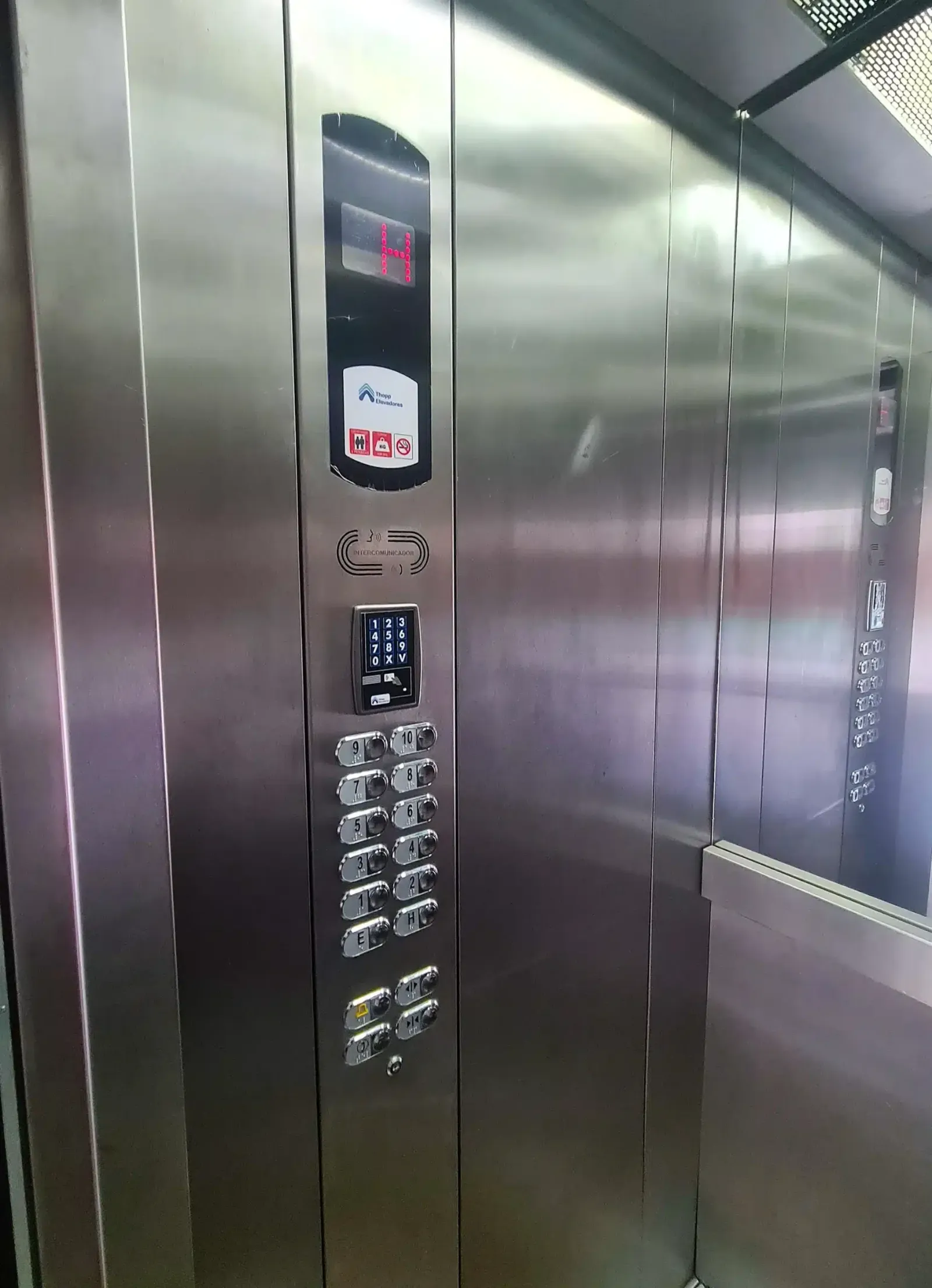 Interior da cabine depois da renovação, com coluna de botoeira nova em inox, indicador digital de andar, botões com identificação em braile e sinalização da Thopp